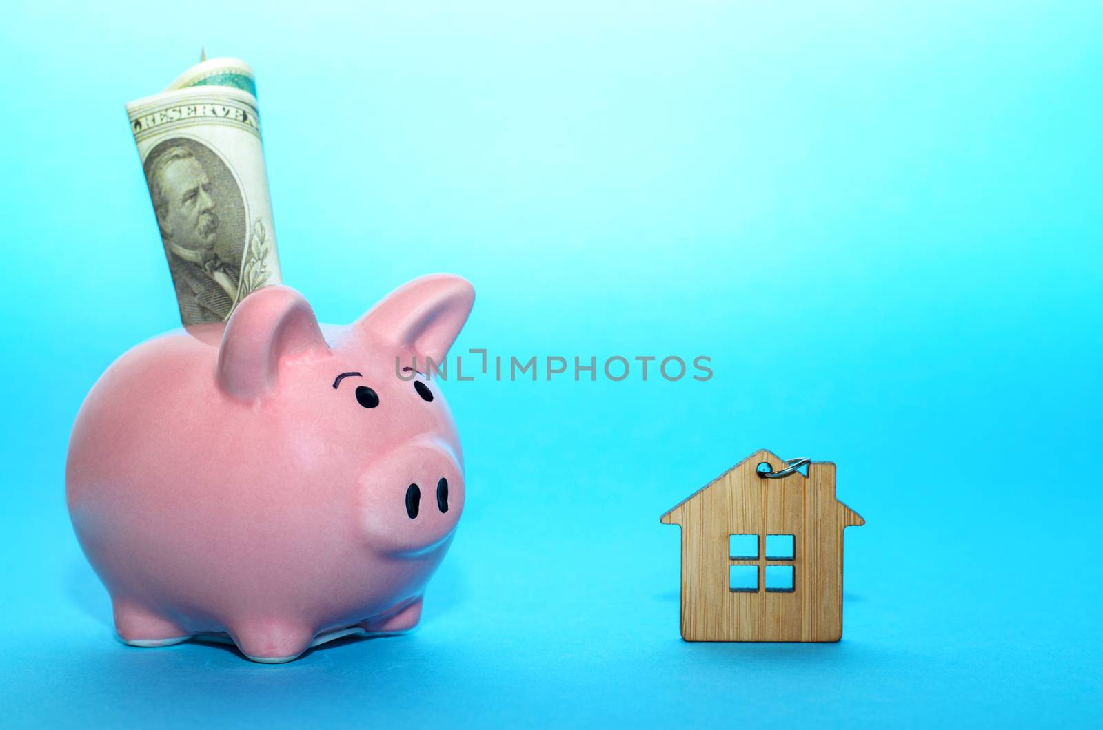 Pink piggy bank with a house on the table. Tinted. Concept of saving finances and real estate deposits