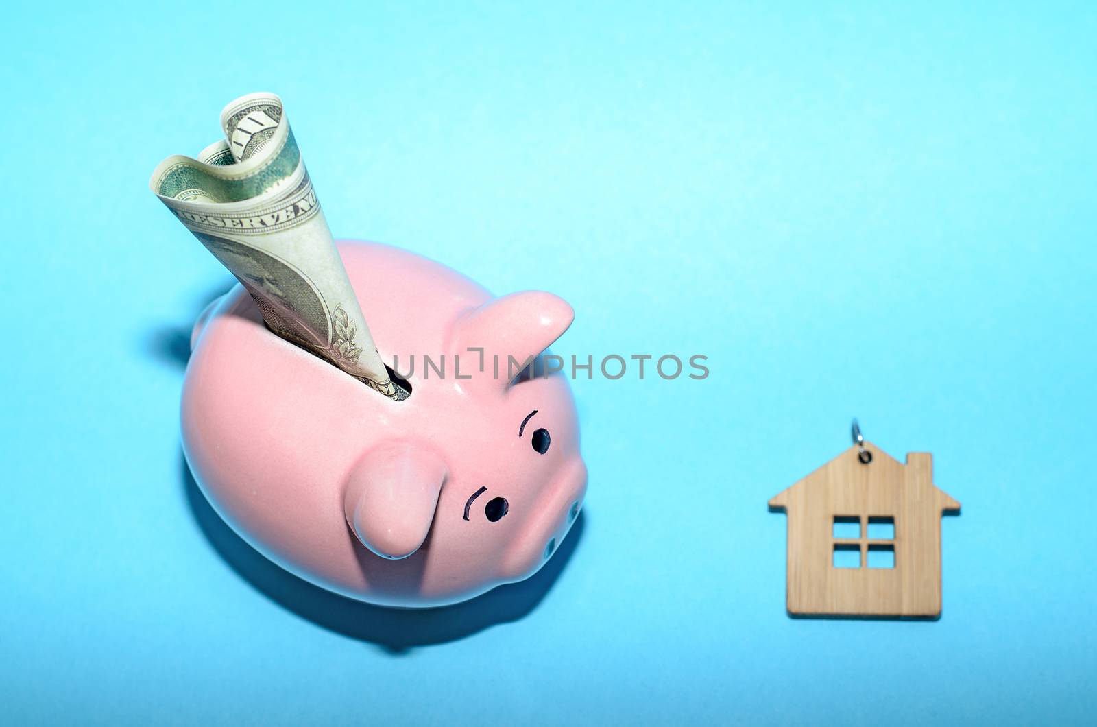 Pink piggy bank with a house on the table. Tinted. Concept of saving finances and real estate deposits