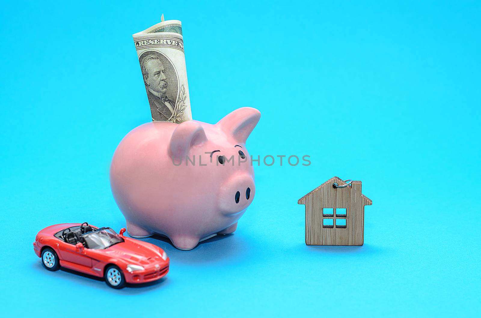 Pink piggy piggy bank with a house and a car on the table. Tinted. Concept of saving finances and real estate deposits