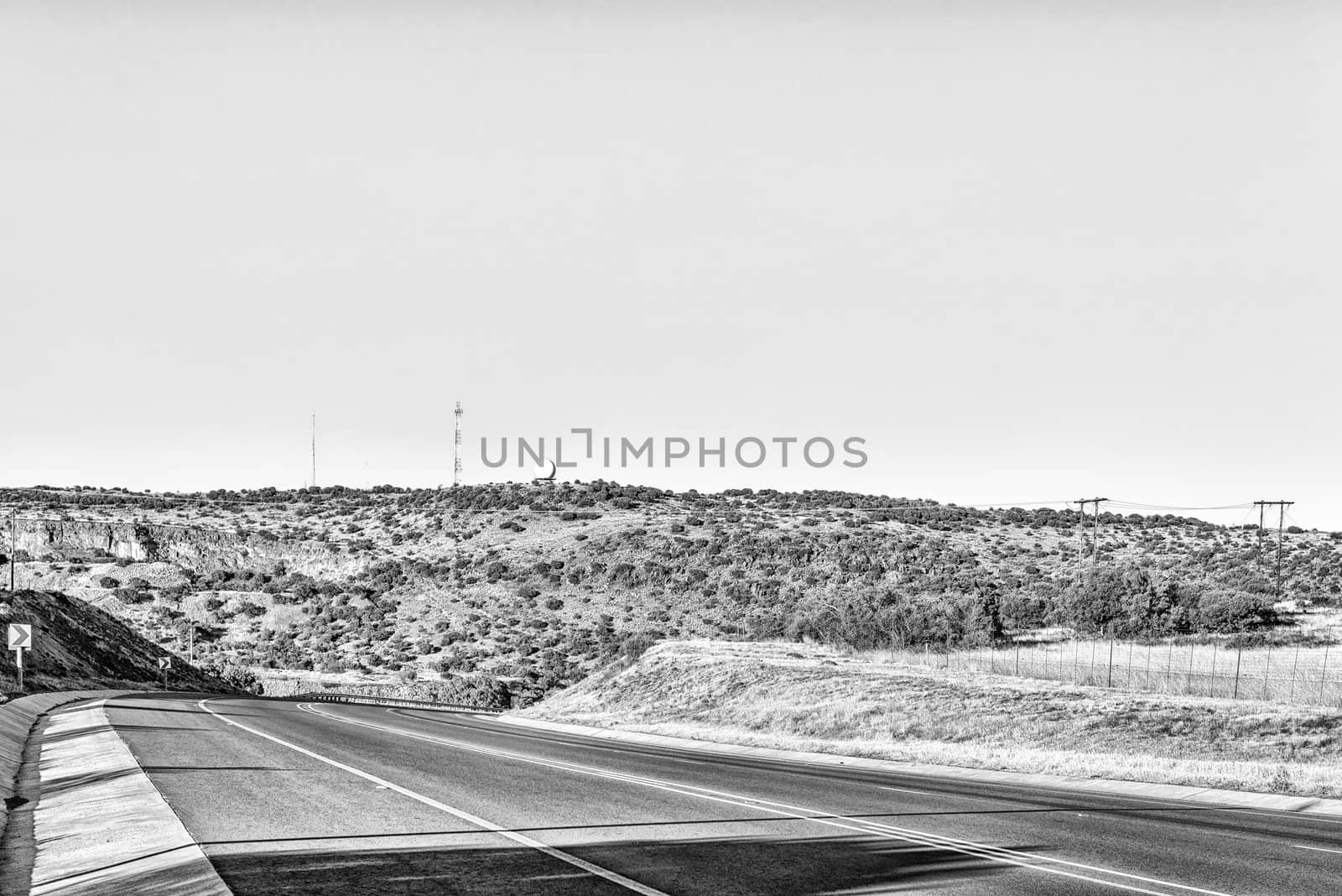 A view of the N8-road to the west of Bloemfontein in the Free State Province of South Africa. A weather radar system and cellphone tower is visible. Monochrome