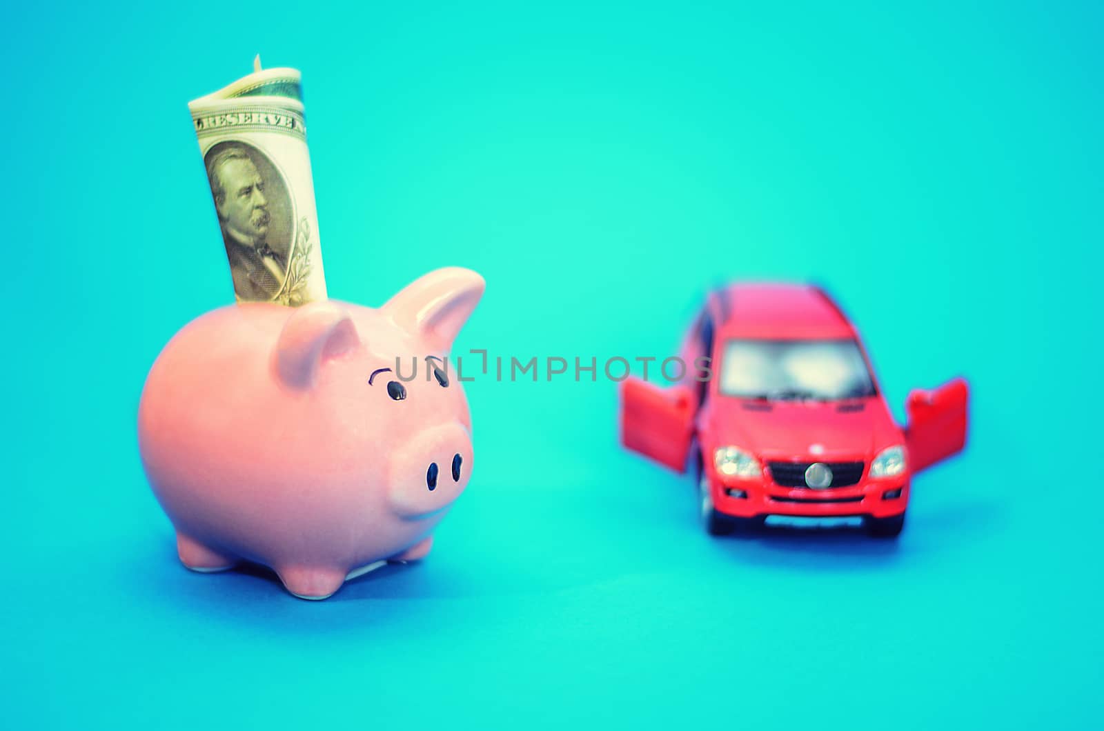 Pink piggy bank with a car on the table. Tinted. Concept of saving finances and contributions to property