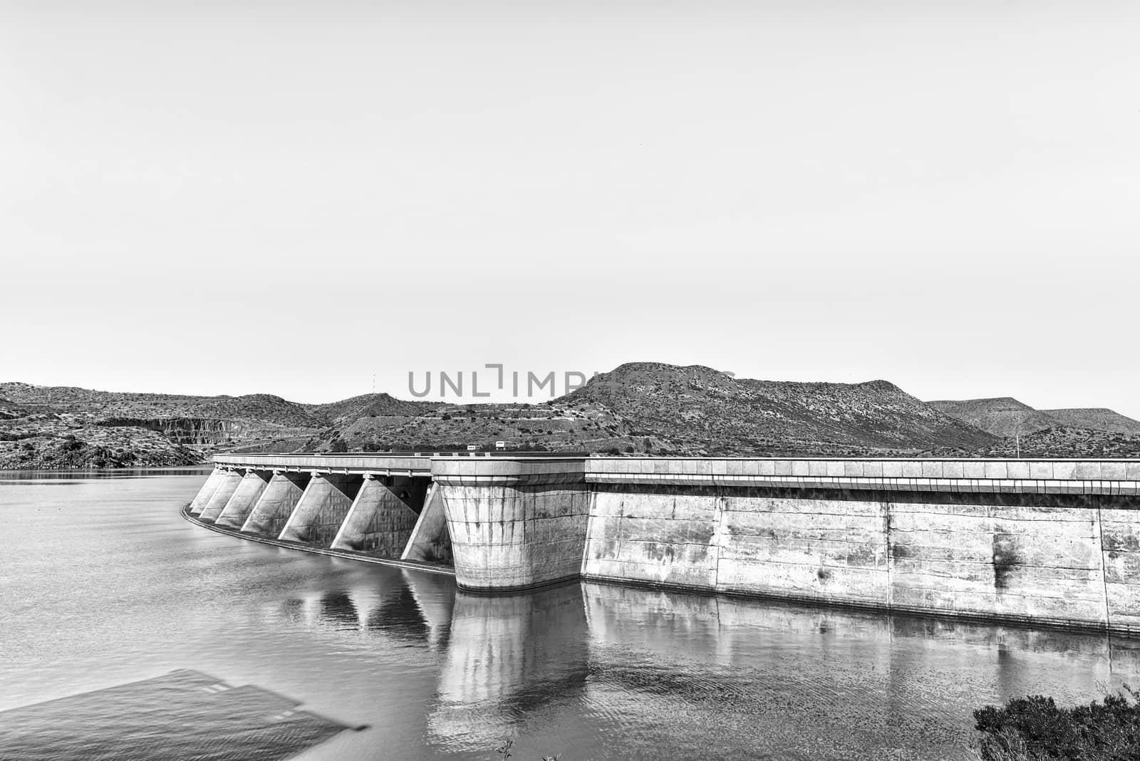 Wall of the Vanderkloof Dam in the Orange River. The Vanderkloof town in the Northern Cape Province is visible on the hills in the back. Monochrome