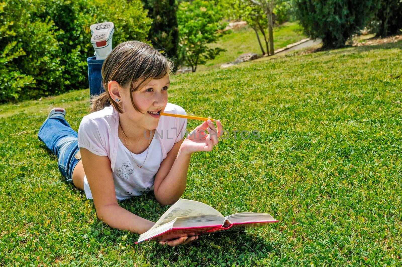 Girl resting with a book on the grass in the park. thought looking to the side