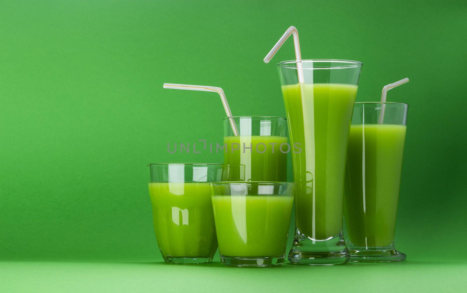 Organic green smoothie, glass of apple juice isolated on green background with copy space, fresh celery cocktail with straw, collection