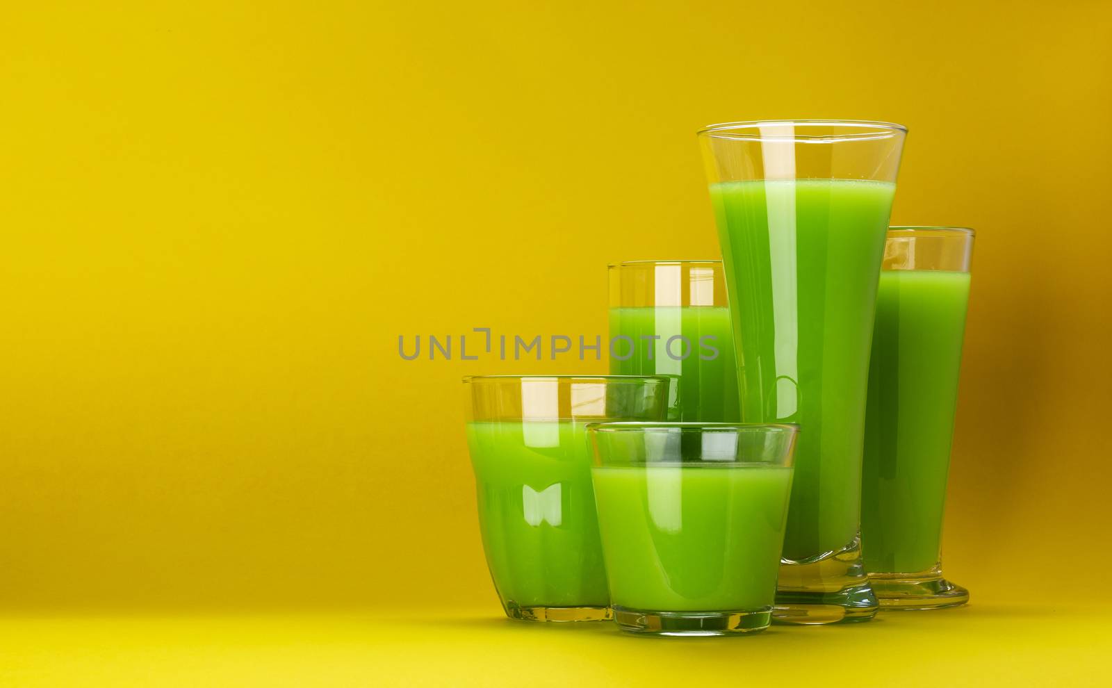 Organic green smoothie, glass of apple juice isolated on yellow background with copy space, fresh celery cocktail, collection