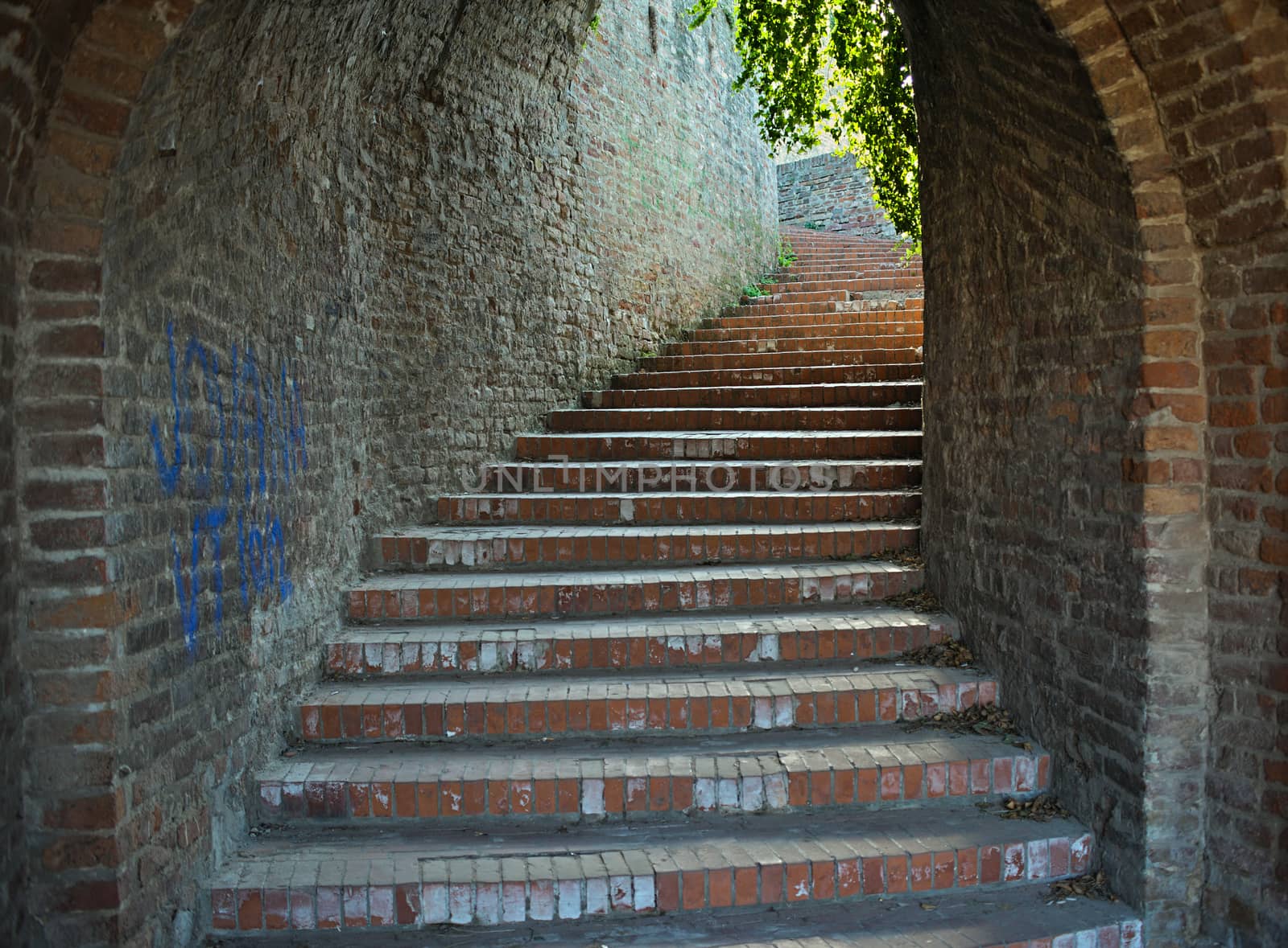 Red bricks stairway tunnel going up with light at the end