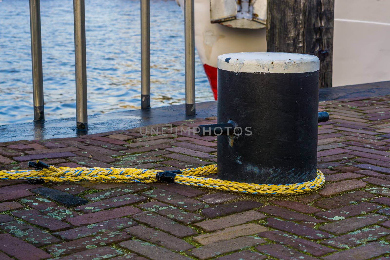 Docking pole with a rope to secure the boat, equipment at the harbor, water transportation background by charlottebleijenberg