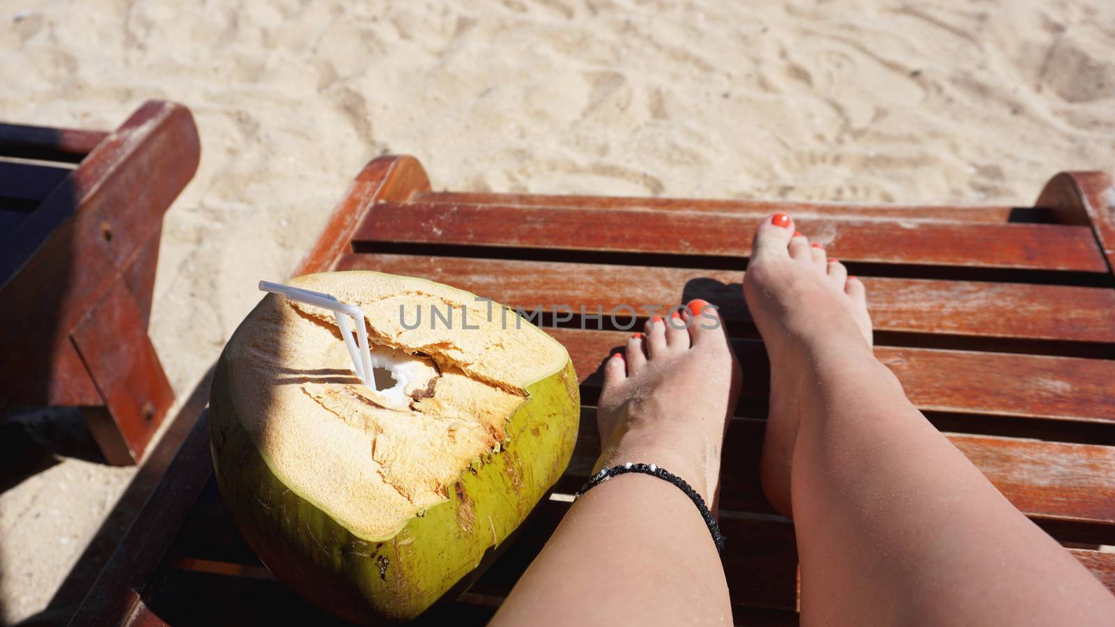Female legs and coconut drink on the beach by natali_brill