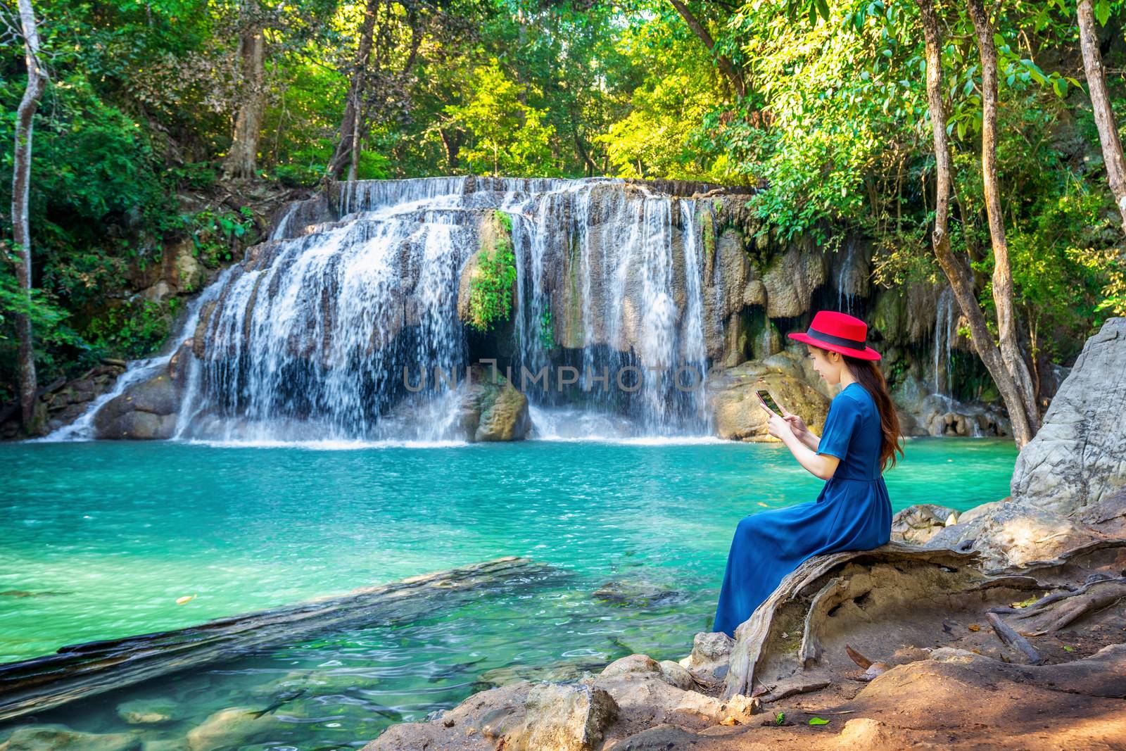 Woman sitting at Erawan waterfall in Thailand. Beautiful waterfall with emerald pool in nature. by gutarphotoghaphy