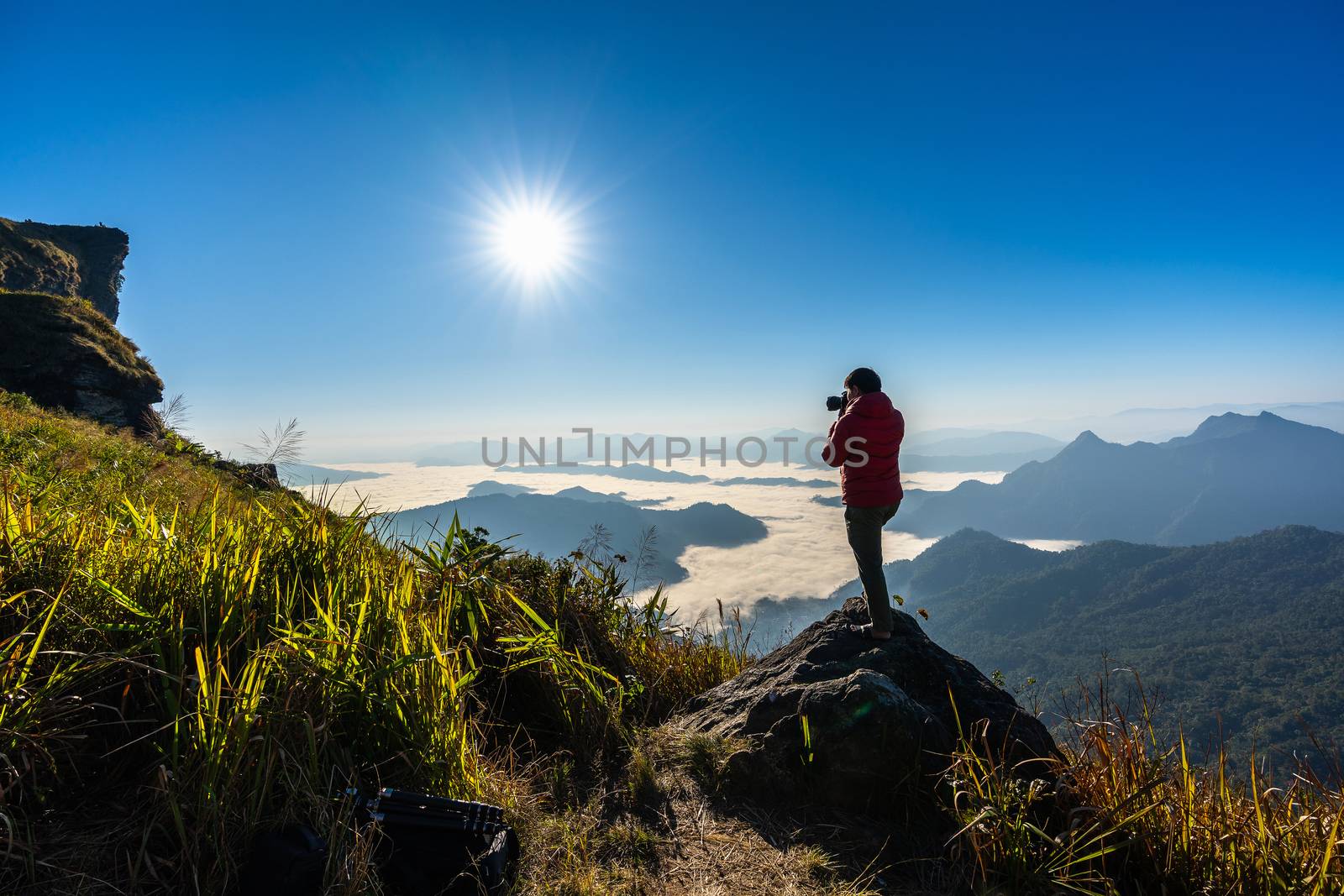 Photographer hand holding camera and standing on top of the rock in nature. Travel concept. by gutarphotoghaphy