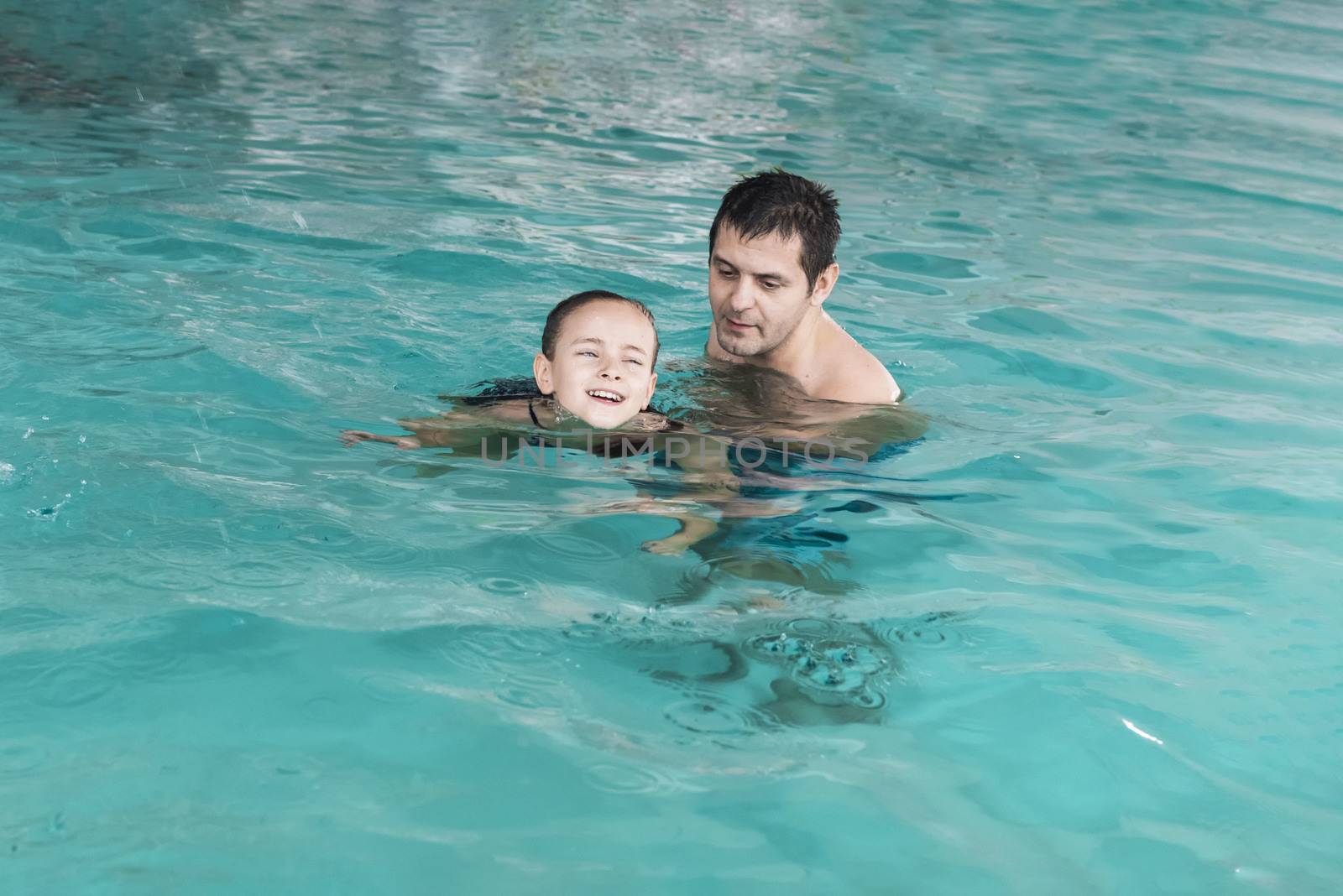 Father teaches girl to swim in the pool. Happy father teaching his little daughter to swim. Active happy child learning to swim. Little girl in a pool .