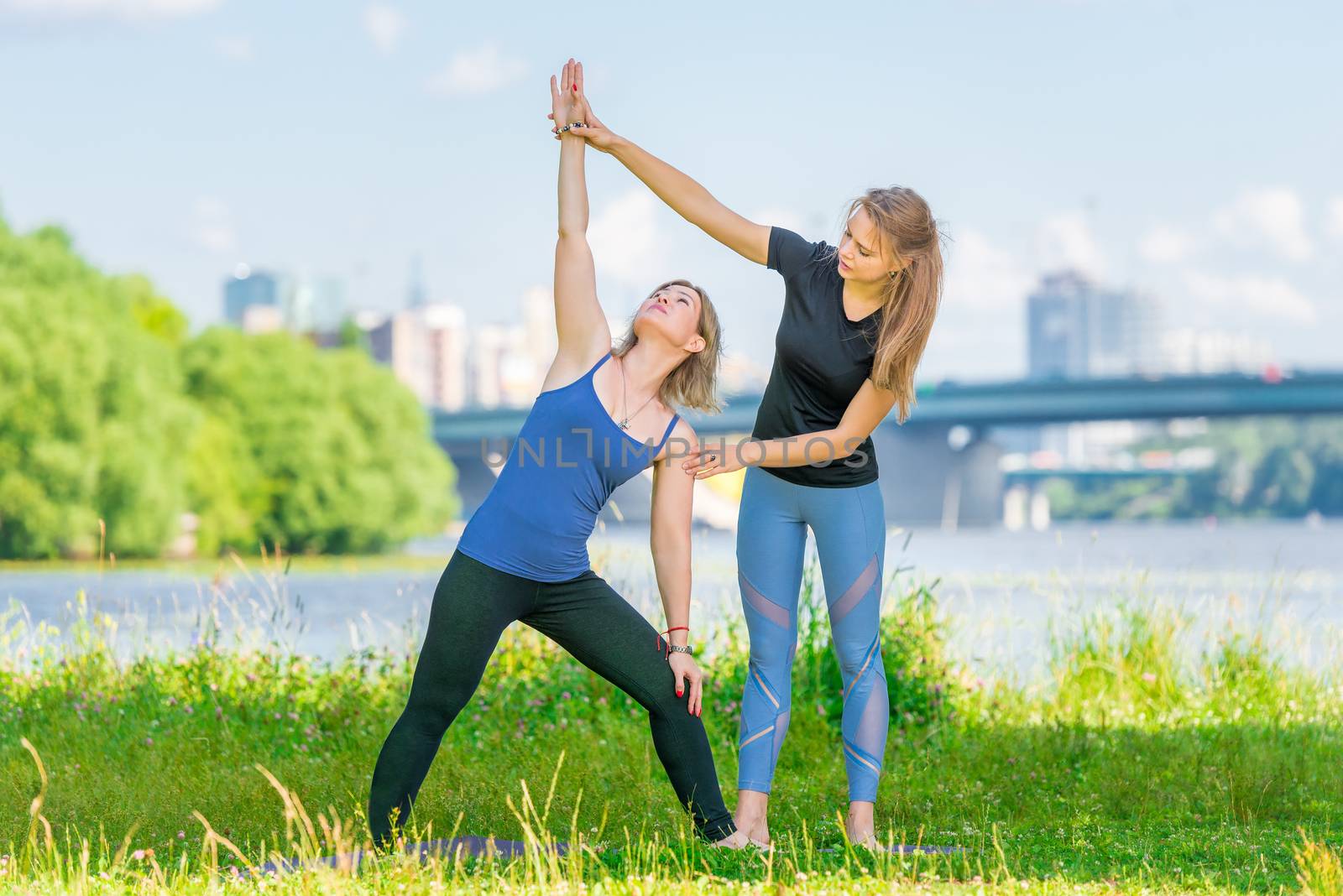 Woman of 40 years doing yoga under the supervision of a trainer in the fresh air in the park in summer