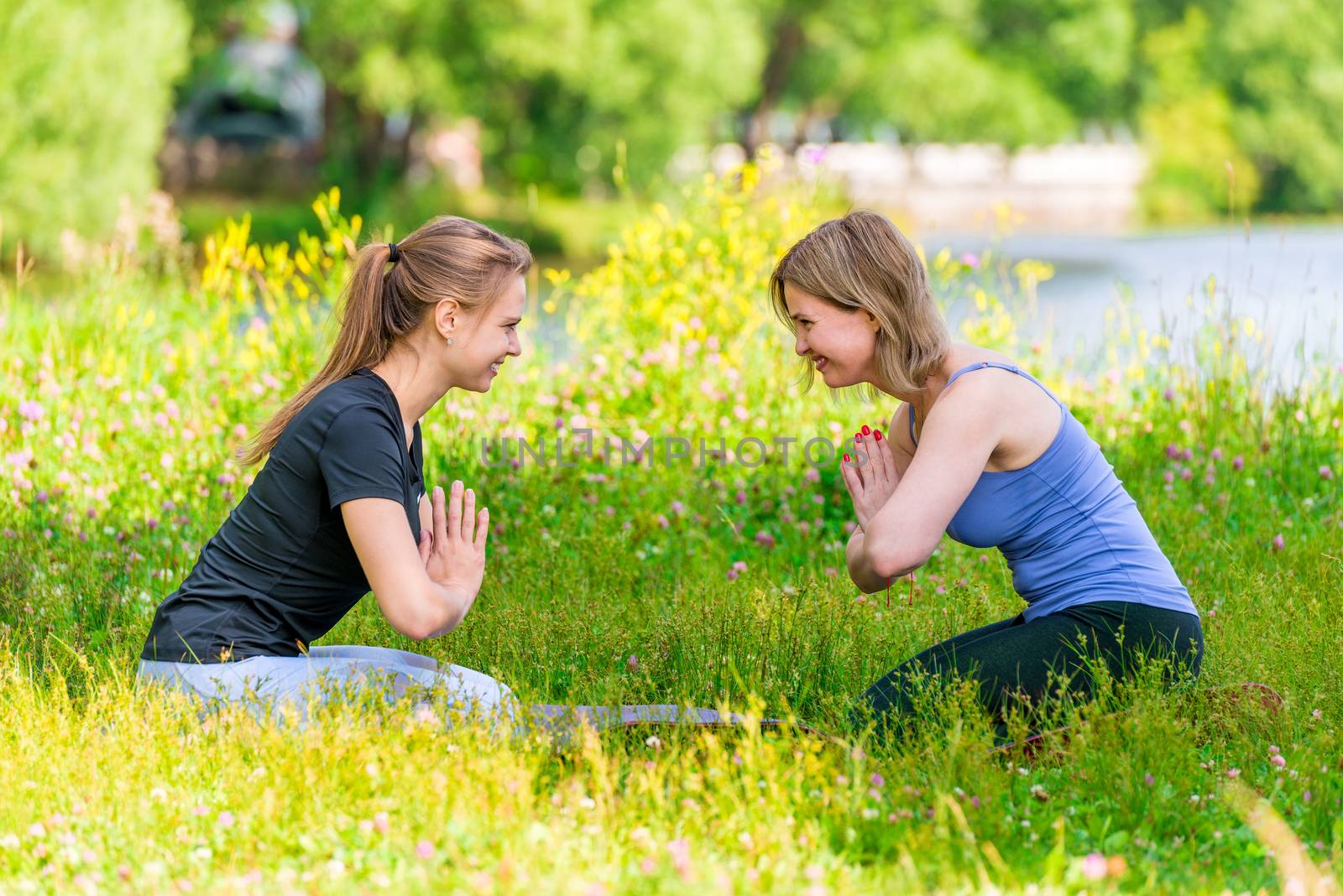 Woman with a young trainer at the yoga class in the summer park by kosmsos111