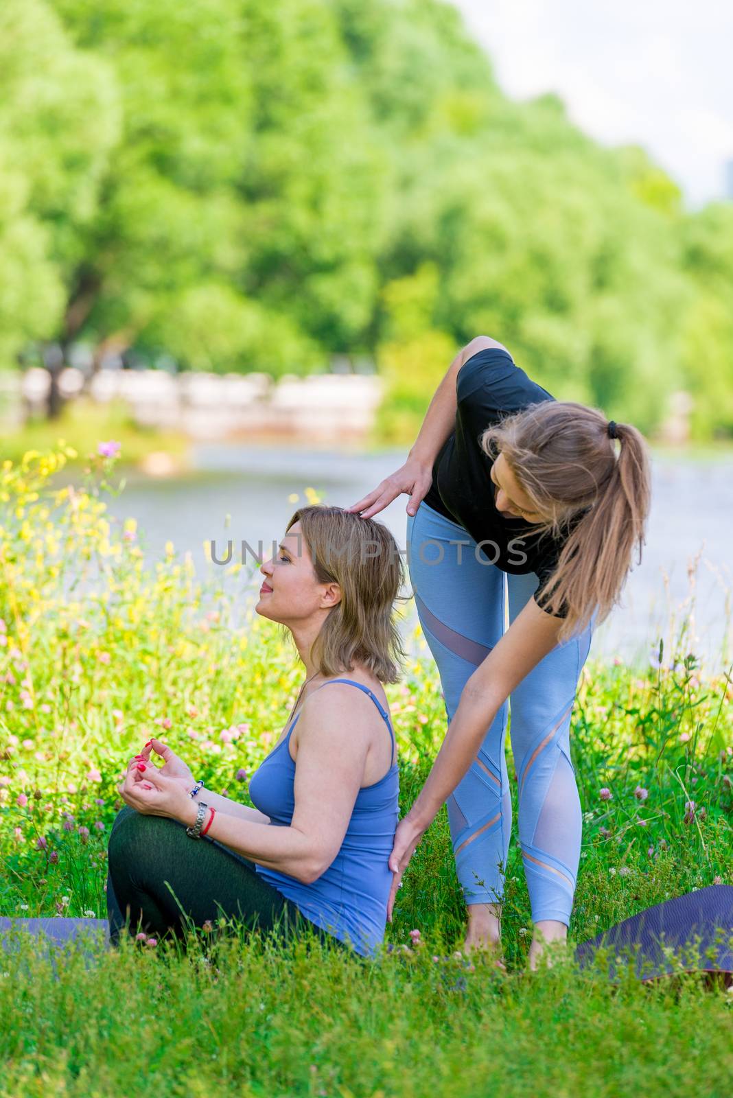 trainer and woman at the yoga class in the lotus position on the by kosmsos111