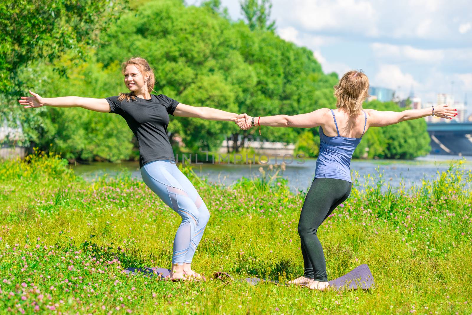 yoga trainer in class with a mature woman exercising in a summer by kosmsos111