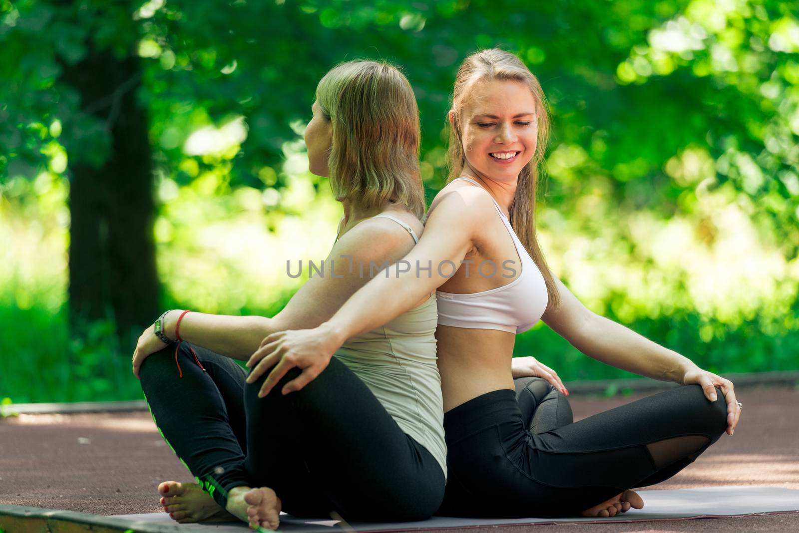 Classes with an individual yoga trainer in the park on a sunny summer day, portrait of active women