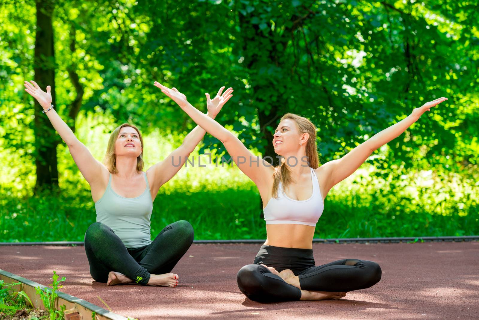 woman and her trainer in the lotus position doing yoga in the pa by kosmsos111