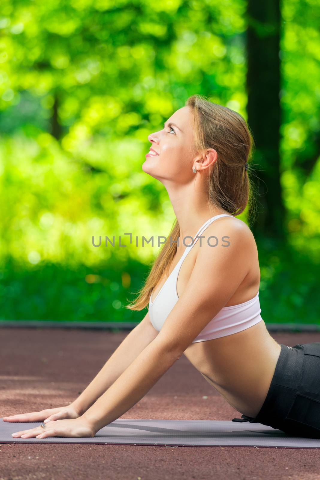 young slim woman doing stretching exercises in the park in the f by kosmsos111