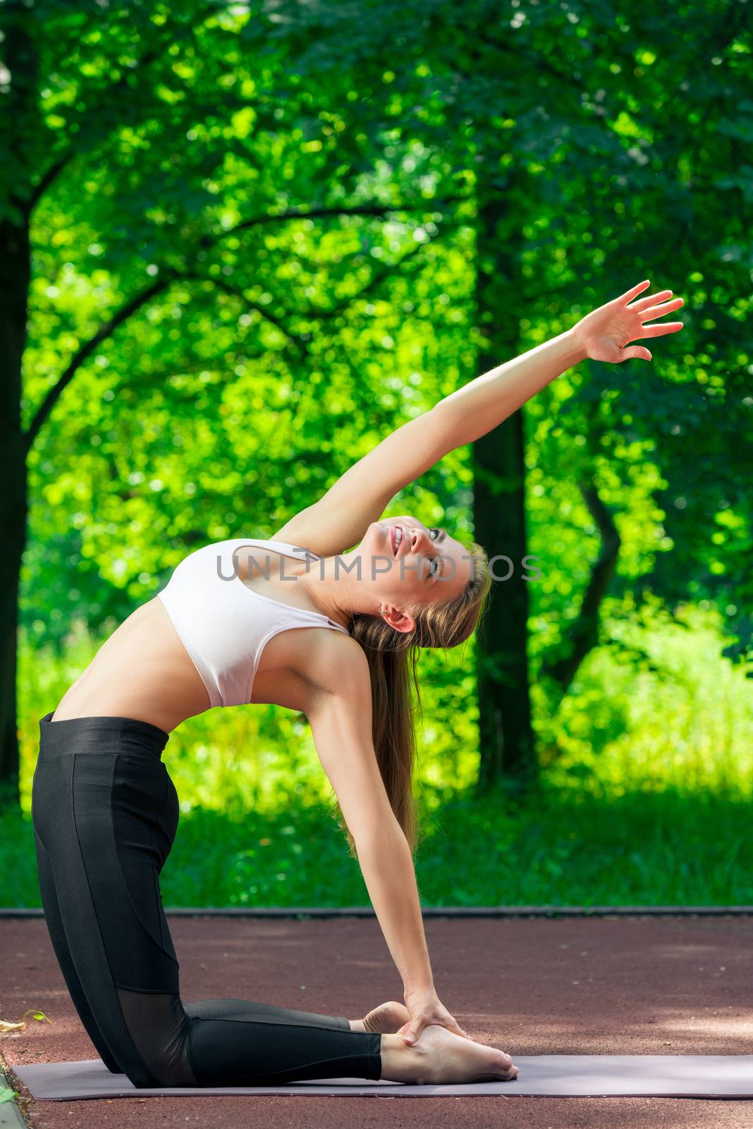 flexible slim girl doing yoga in the park on a summer day