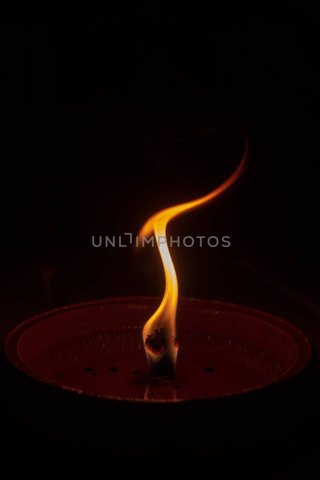 Candle flame close up on dark background, interesting flame figure, candle fire shaped like human statue