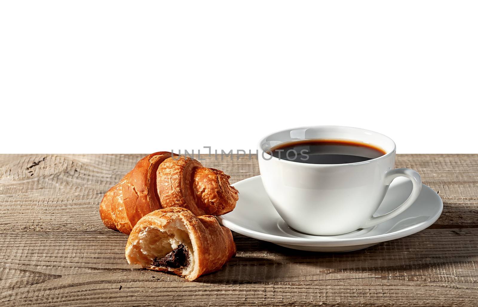 Coffee and croissants on a wooden table. Broken croissant. Isolated on white background.