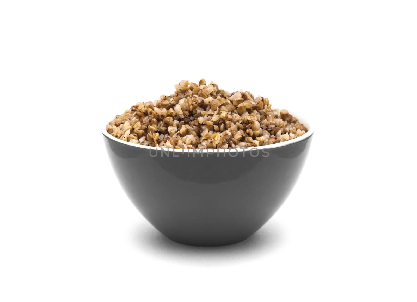 Dry buckwheat in grey color ceramic bowl isolated on white background. Isolated on white background.