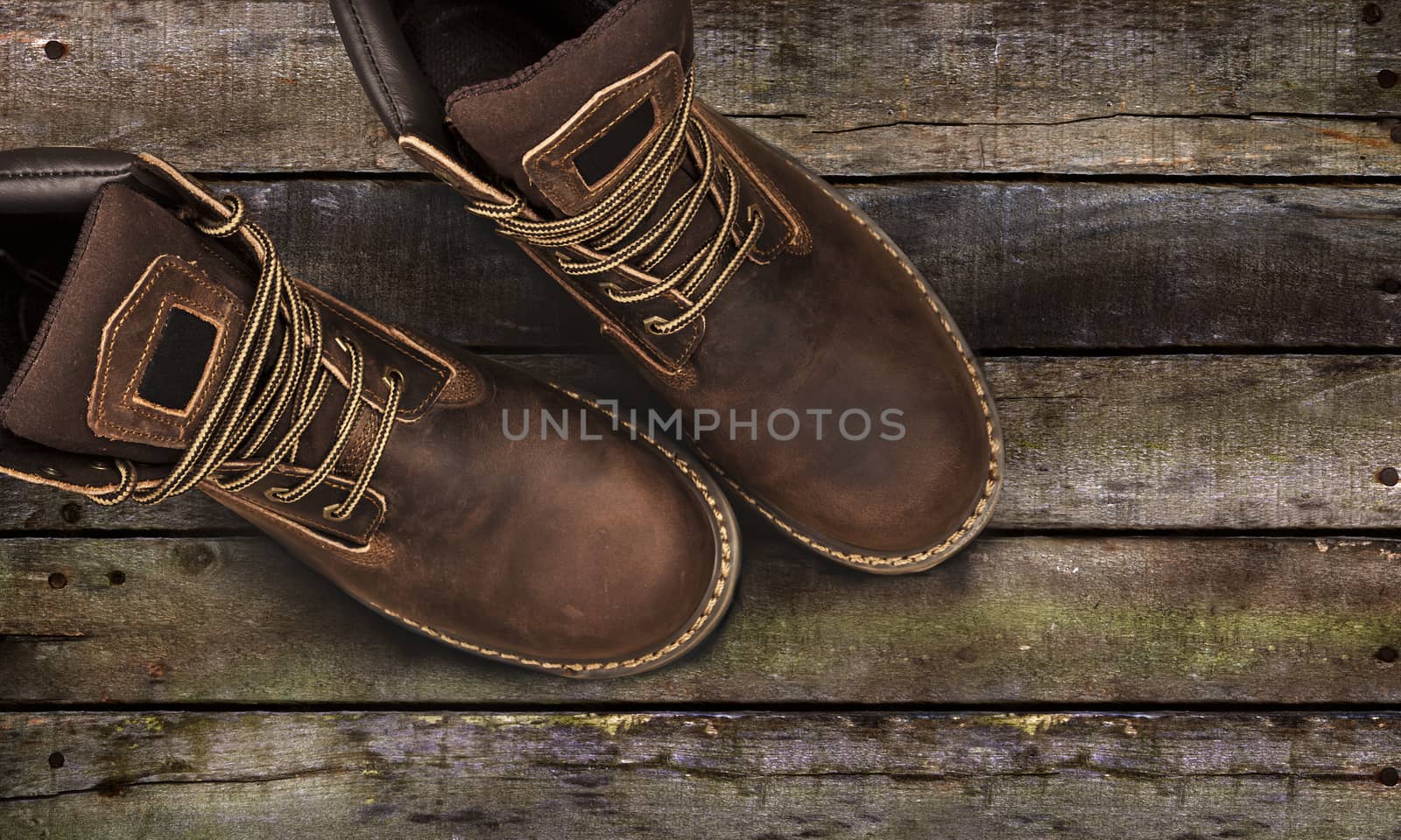 Brown men's boots, on a wooden background. Closeup isolated