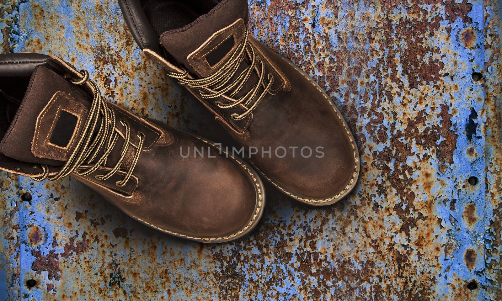 Men's brown boots on old rusty background. Closeup isolated