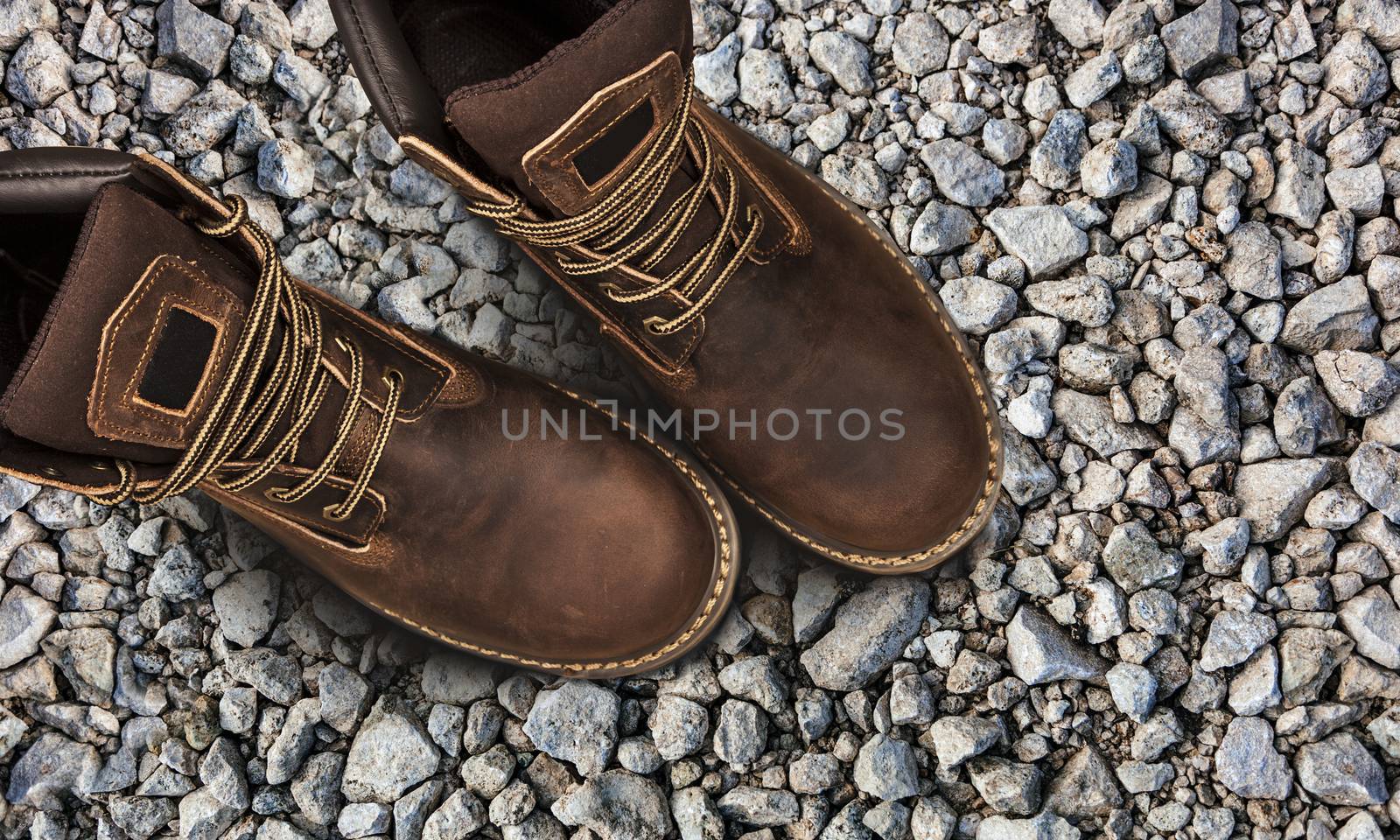 Men's brown boots on stone gravel background. Closeup isolated