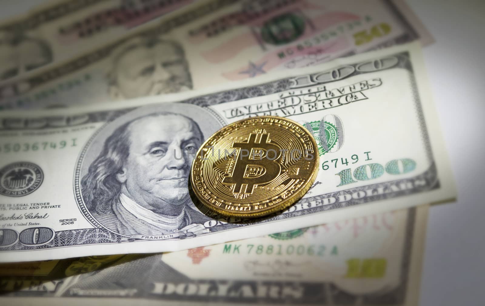 Golden bitcoin coin on us dollars isolated on close up.