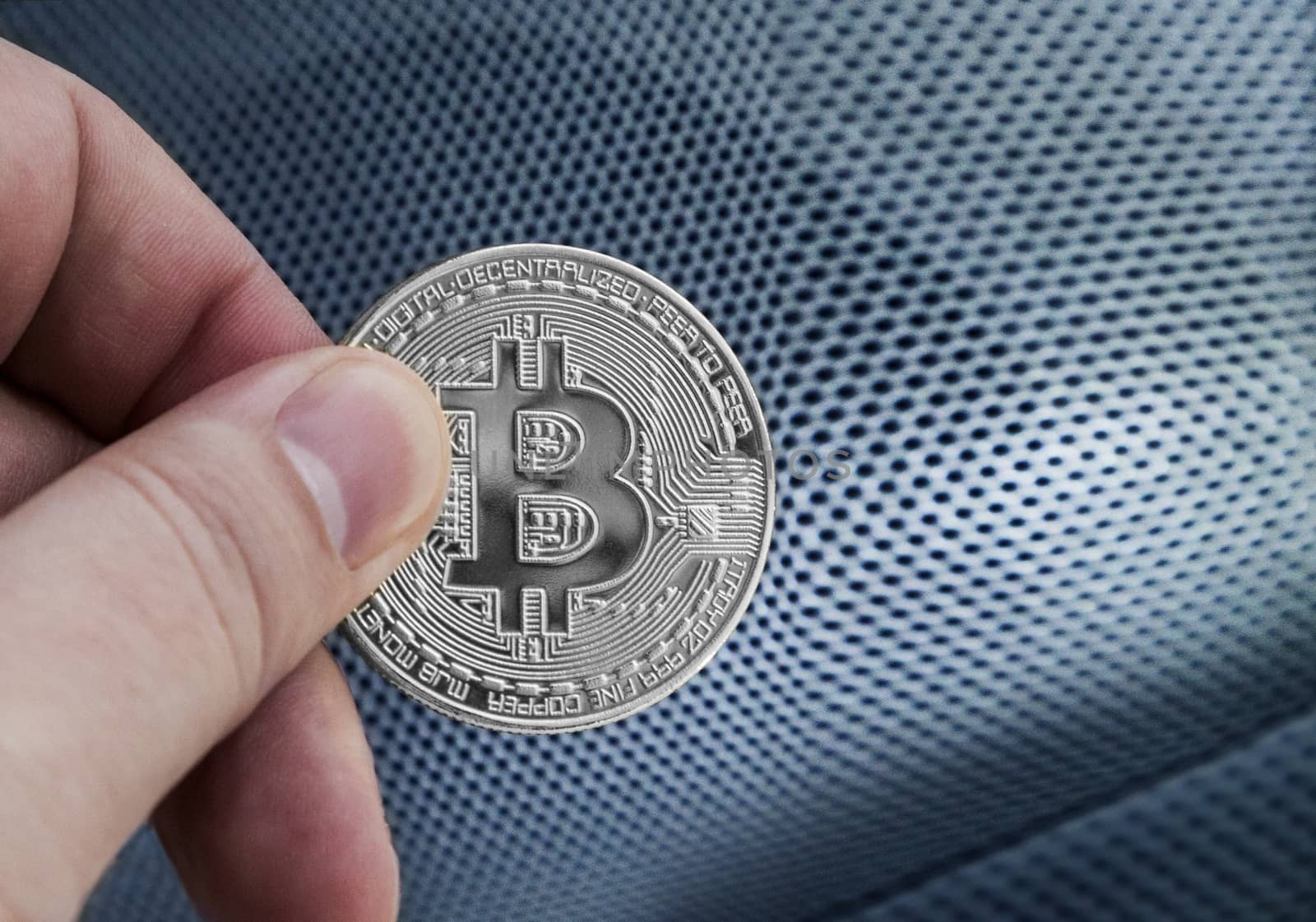 man's hand holding silver Bitcoin on a white background