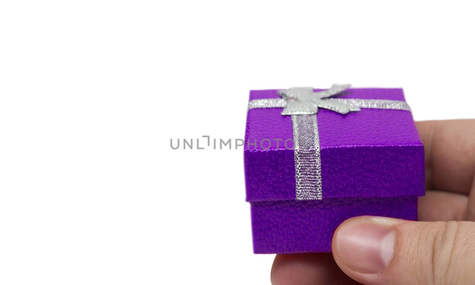 Hand holding small violet gift with silver ribbon isolated on white background
