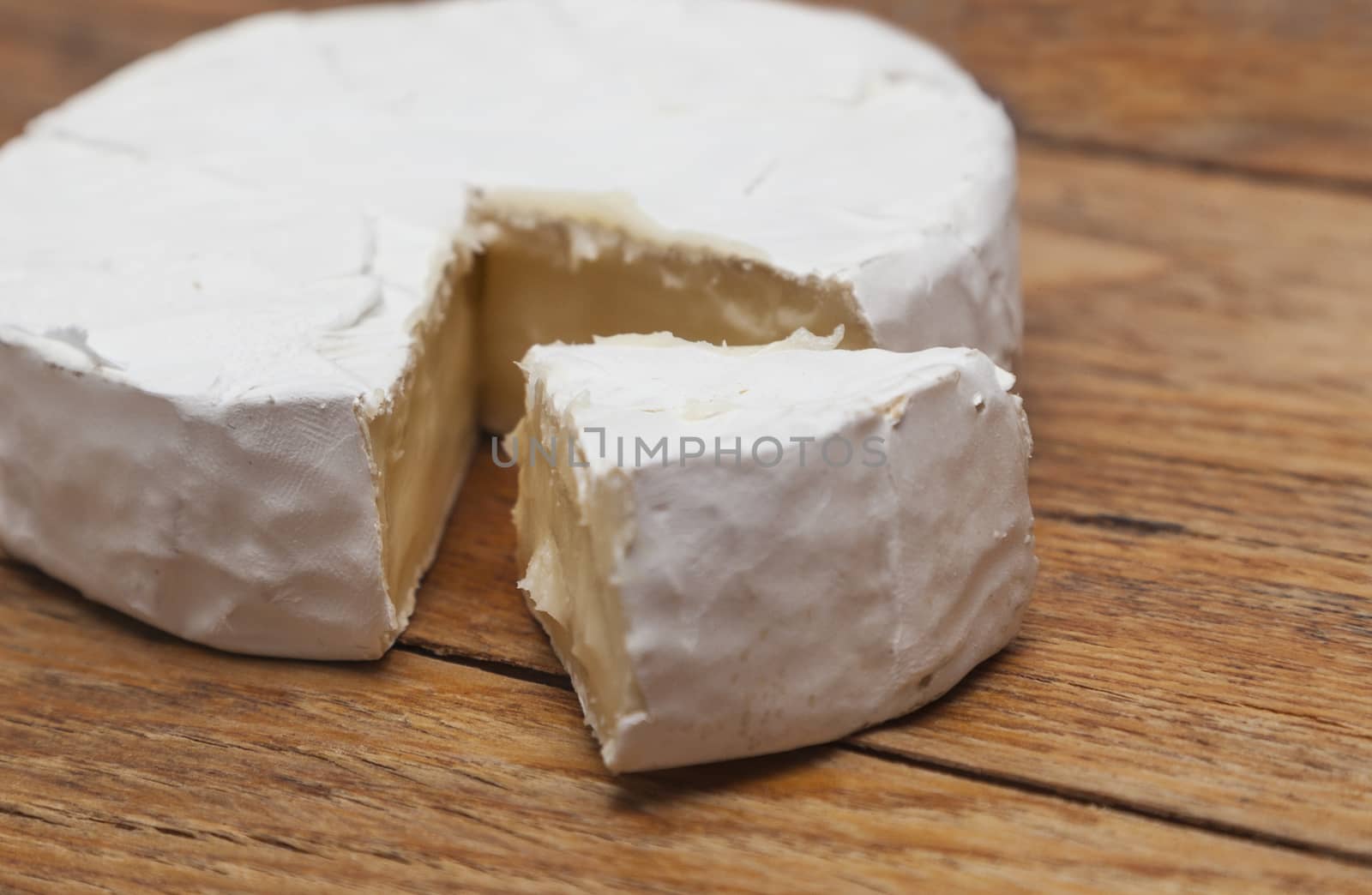 French Camembert cheese on rustic wooden table background