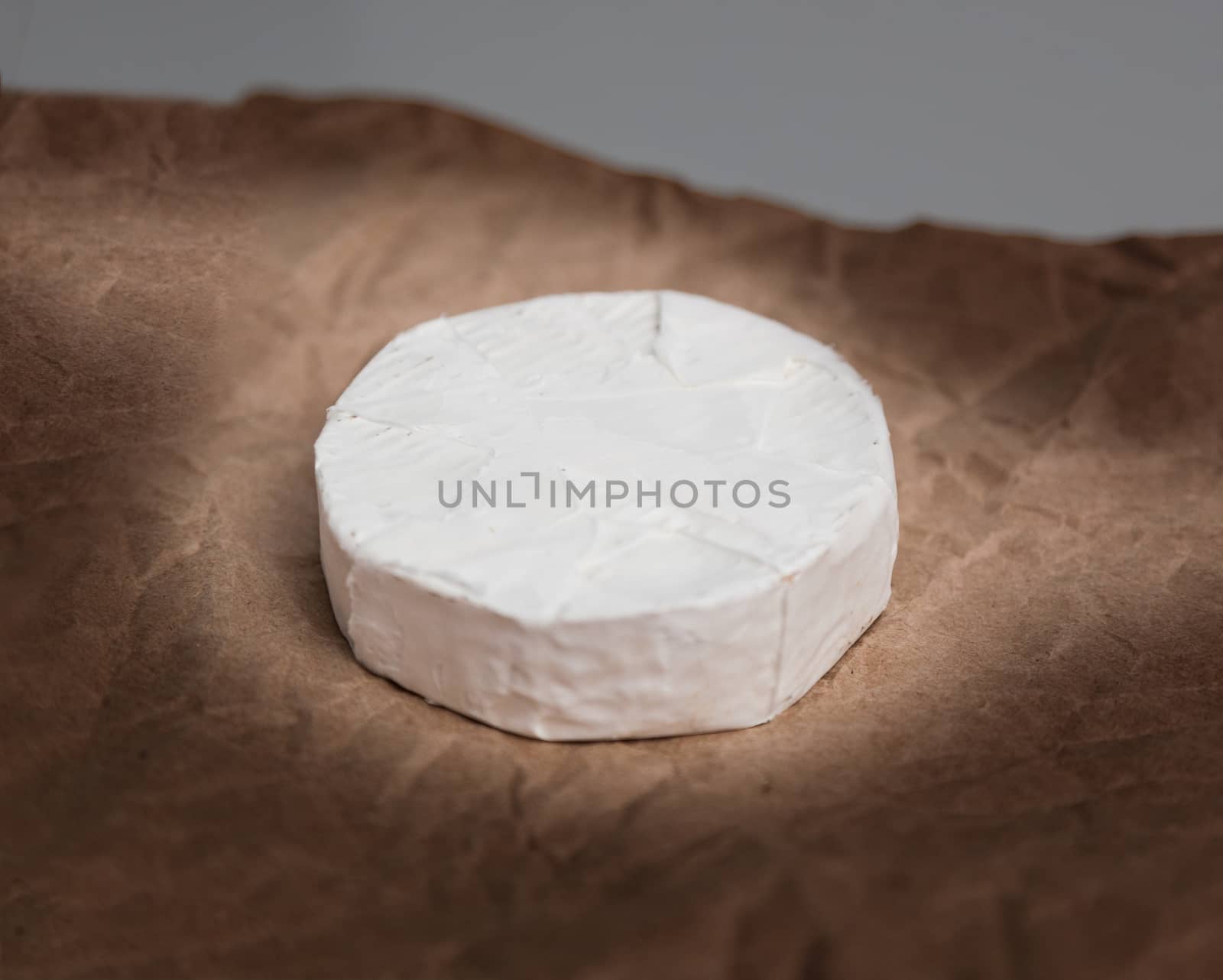 Fresh Camembert cheese is a natural, on Kraft paper brown background. With clipping path