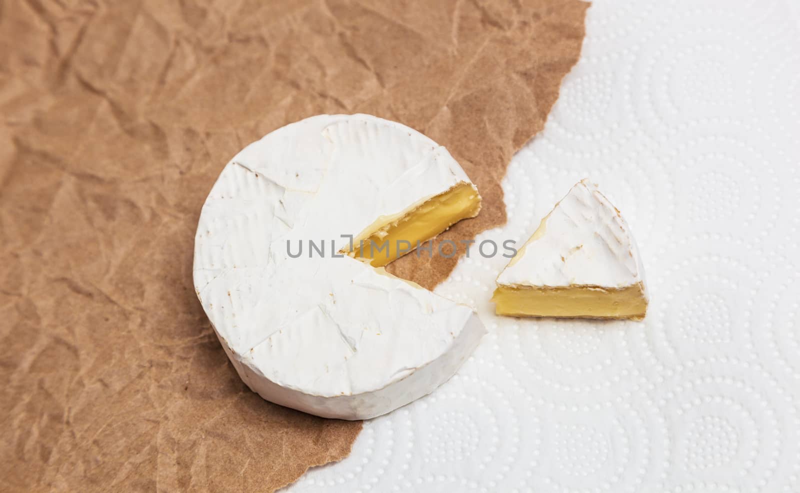 Fresh slice Camembert cheese natural, on Kraft paper brown background. With clipping path