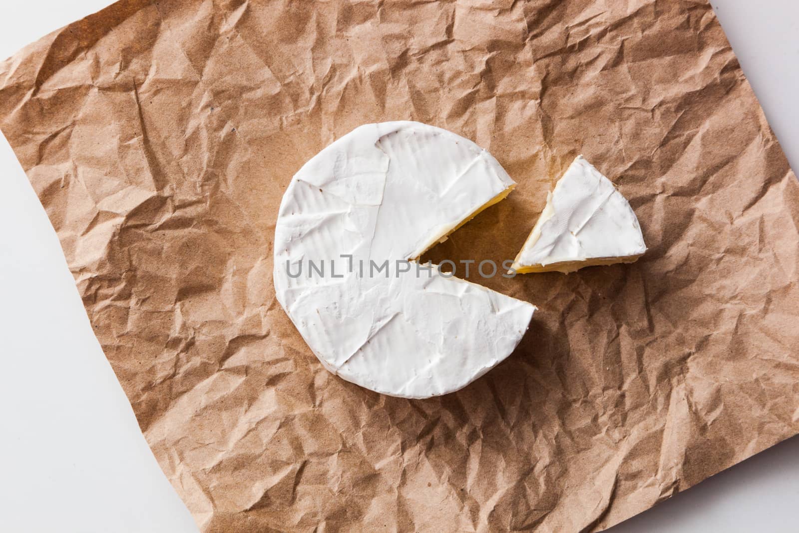 Fresh slice Camembert cheese natural, on Kraft paper brown background. With clipping path