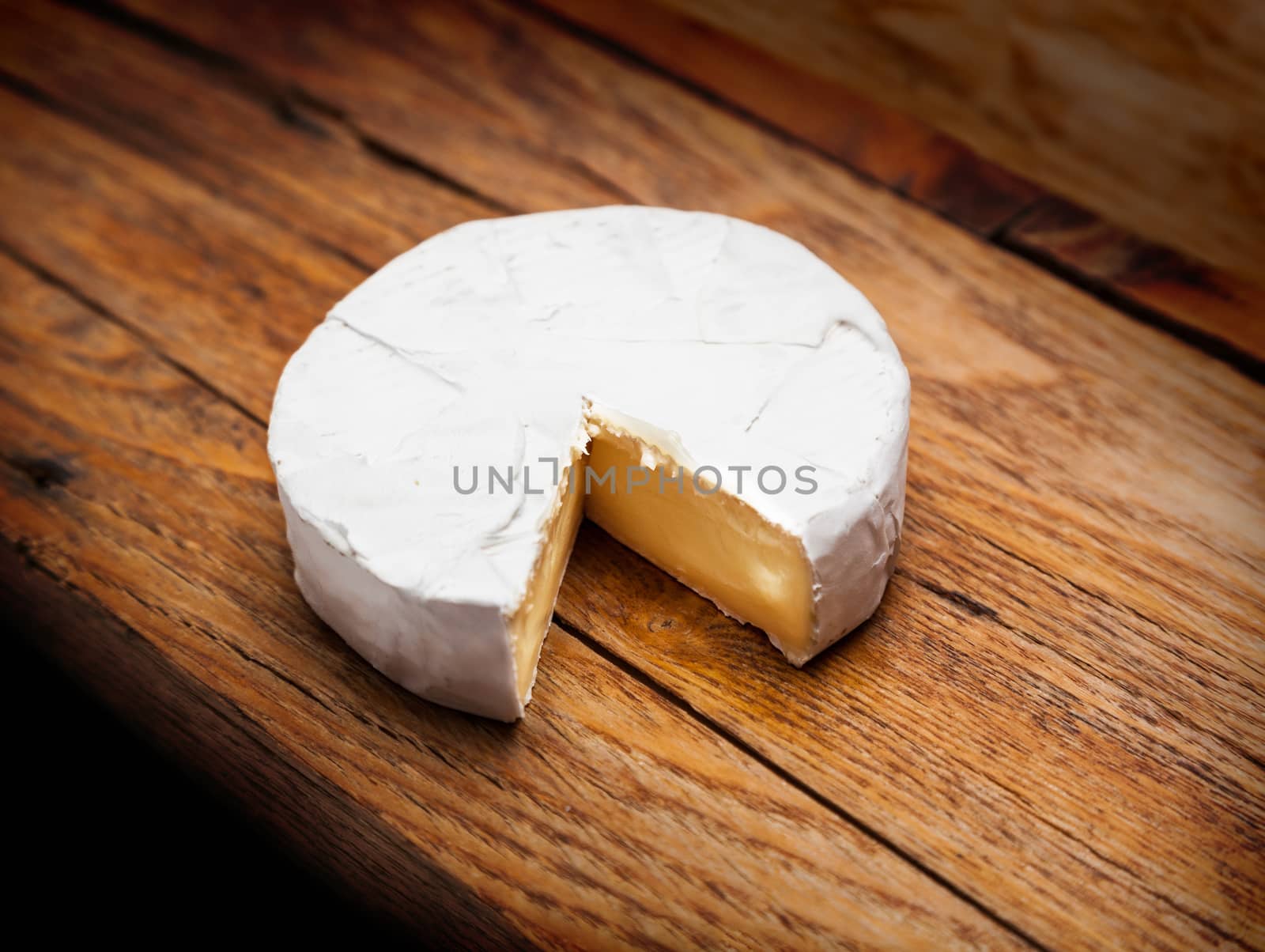 French Camembert cheese on rustic wooden table background