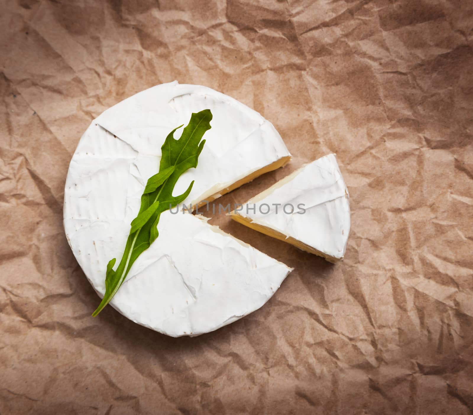 Fresh slice Camembert cheese natural, on Kraft paper brown background. With clipping path
