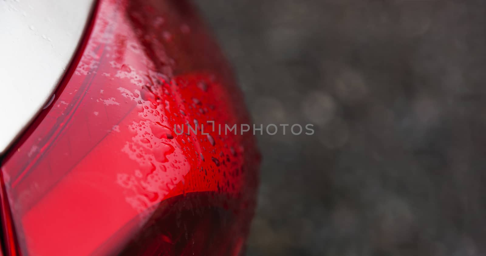 Raindrops on a red car headlight isolated background