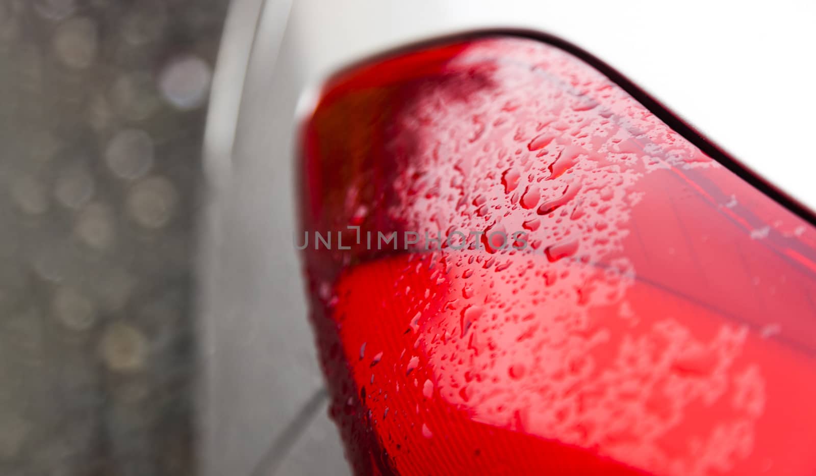 Raindrops on a red car headlight isolated background