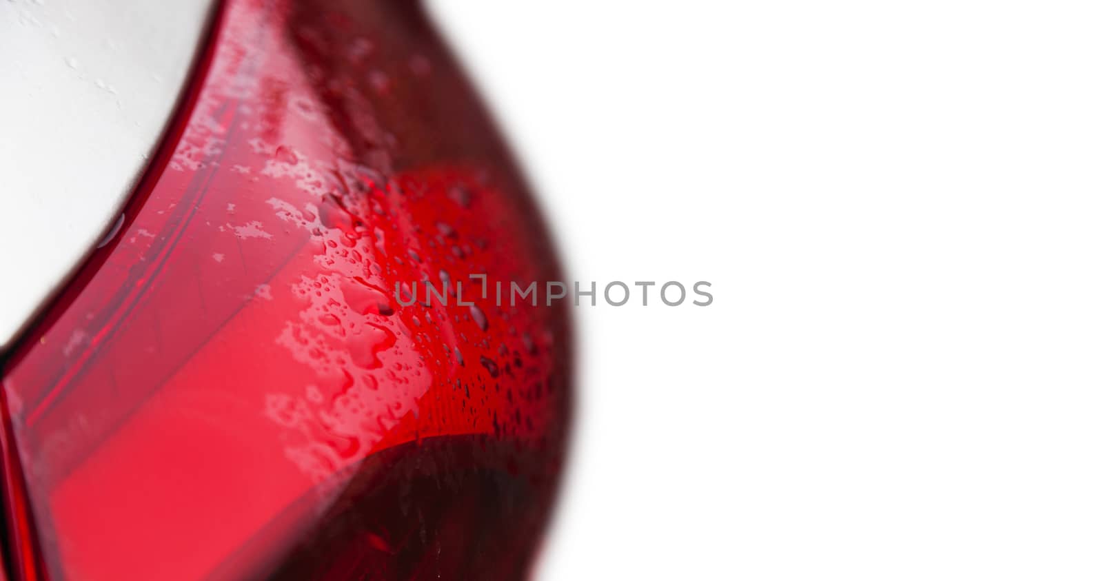 Raindrops on a red car headlight isolated background