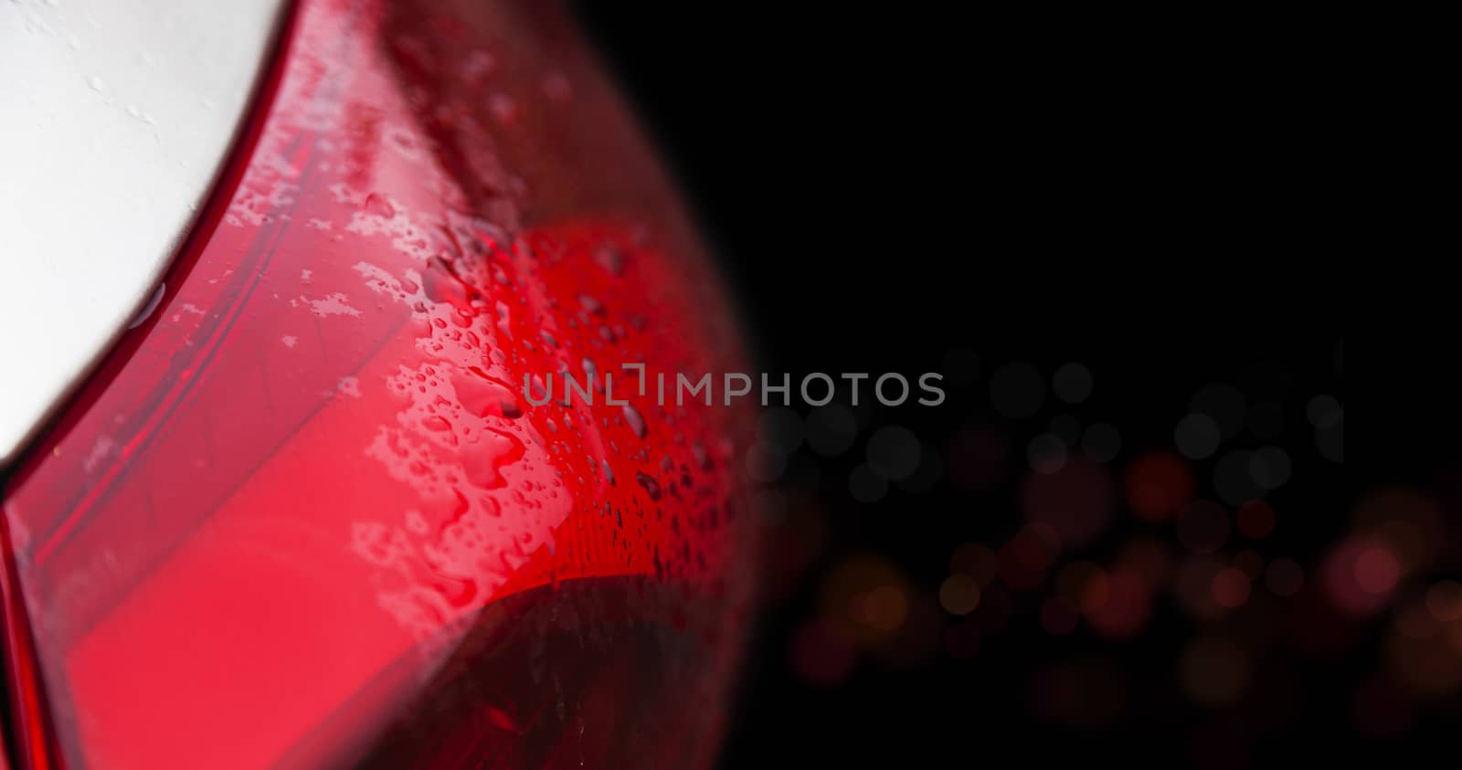 Raindrops on a red car headlight isolated background