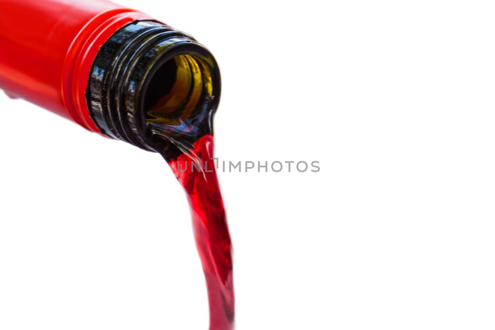 Pouring red wine from bottle into the wineglass on white background. Blurred concept