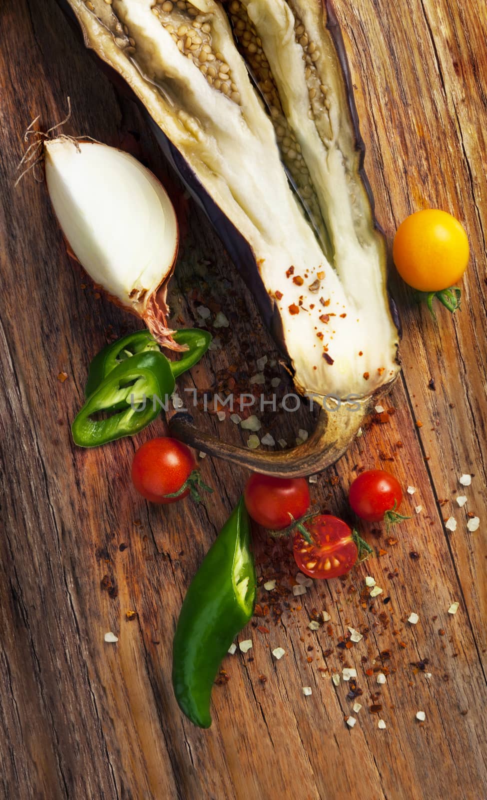 Baked eggplant with tomatoes cherry, onions and chili pepper on wooden table