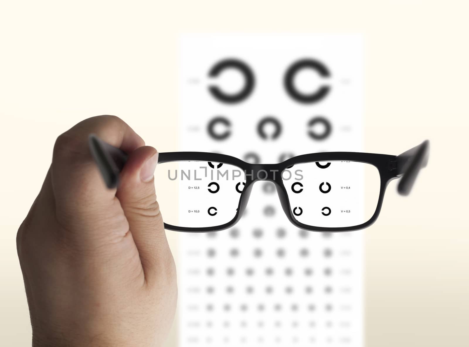 Eyeglasses in hand for eyesight. On the background of a chart test for eyes of Landolt C, isolated