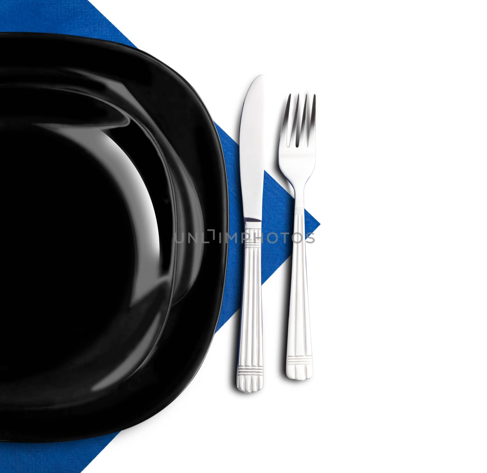 Black plate, fork and knife on blue napkin. Isolated on white.