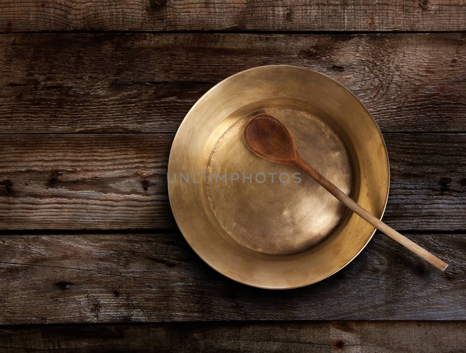 Empty copper tray, wooden spoon on a wooden table. With clipping path