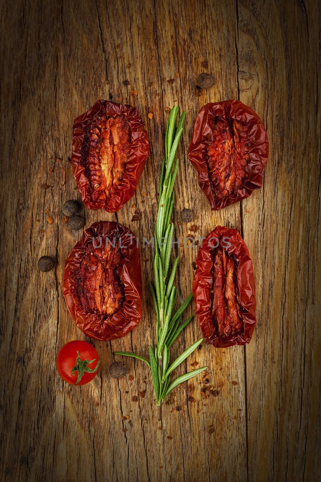 Delicious Dried Tomatoes, a branch of rosemary in a Rustic style, on wood background