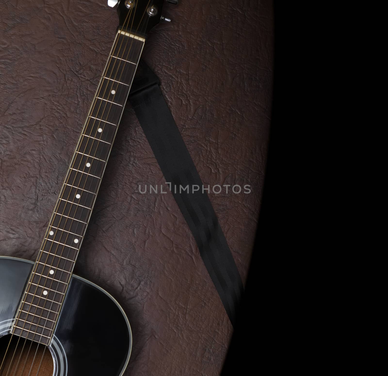 Black acoustic guitar on a background of brown leather