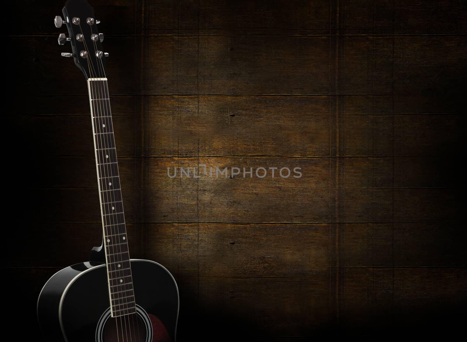 Black acoustic guitar on dark yellow wooden background.